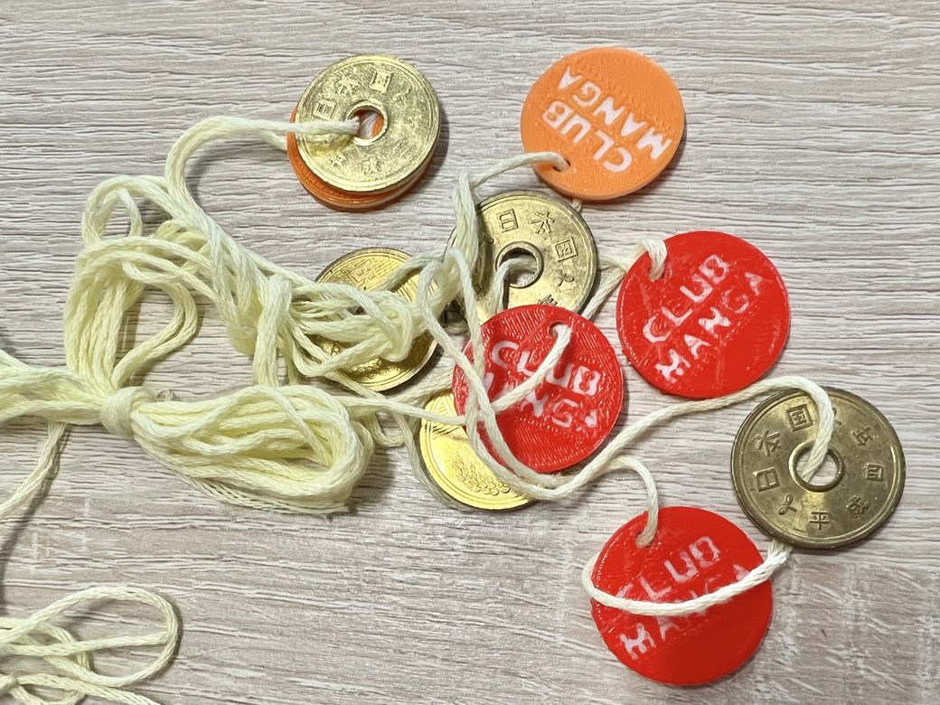 「CLUB MANGA」と書かれたメダルと、五円玉。メダルの裏にはクラブのマスコット『となりのトトロ』が描かれていた（筆者撮影）