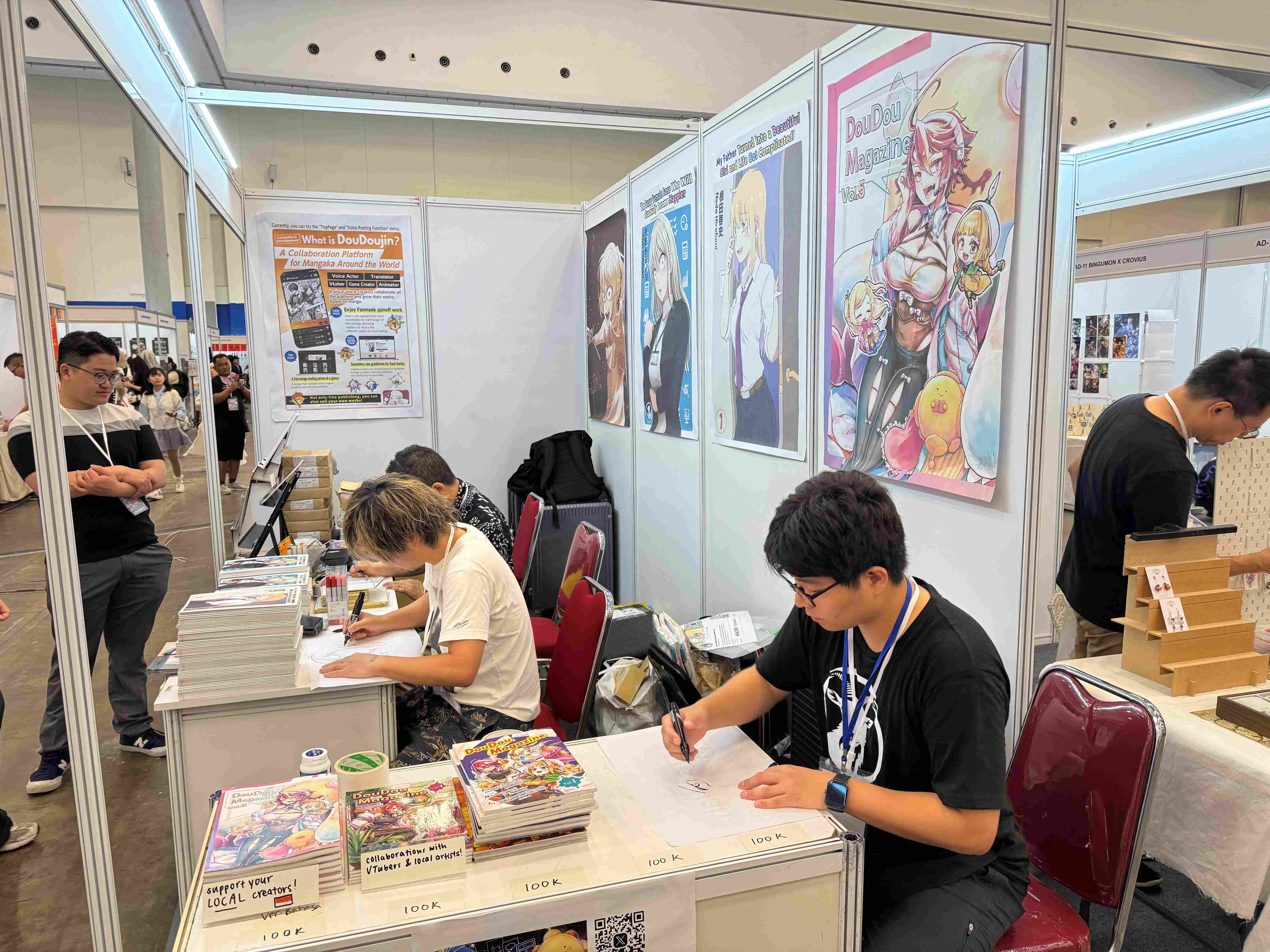 手前には DouDouDoujin 発行の同人雑誌が並ぶ。誌面はインドネシア語に翻訳され、現地ファンも楽しめる。（写真：水谷代表提供）